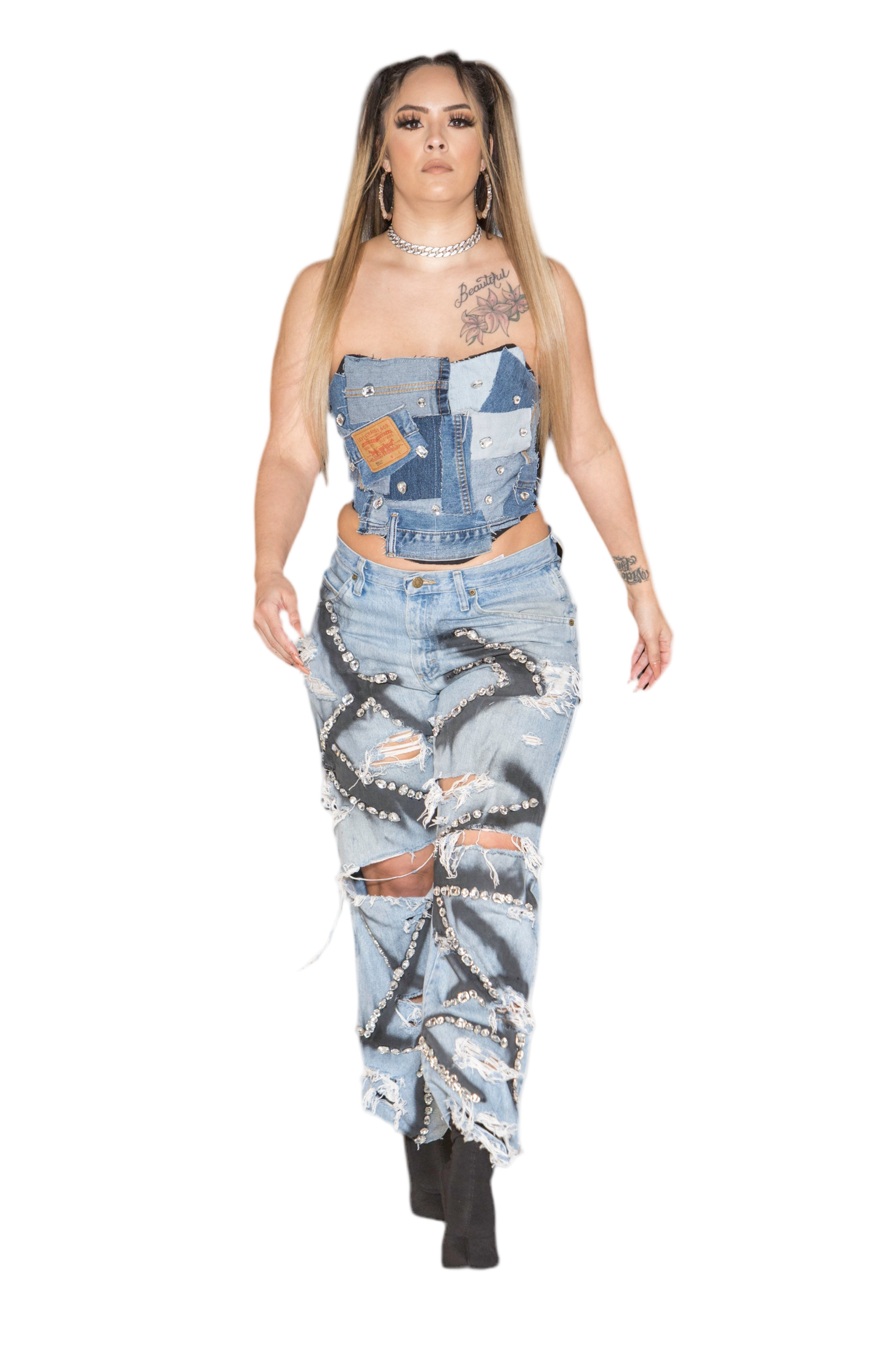 A person wearing a blue denim corset with embellishments and a top over it, standing against a white background.