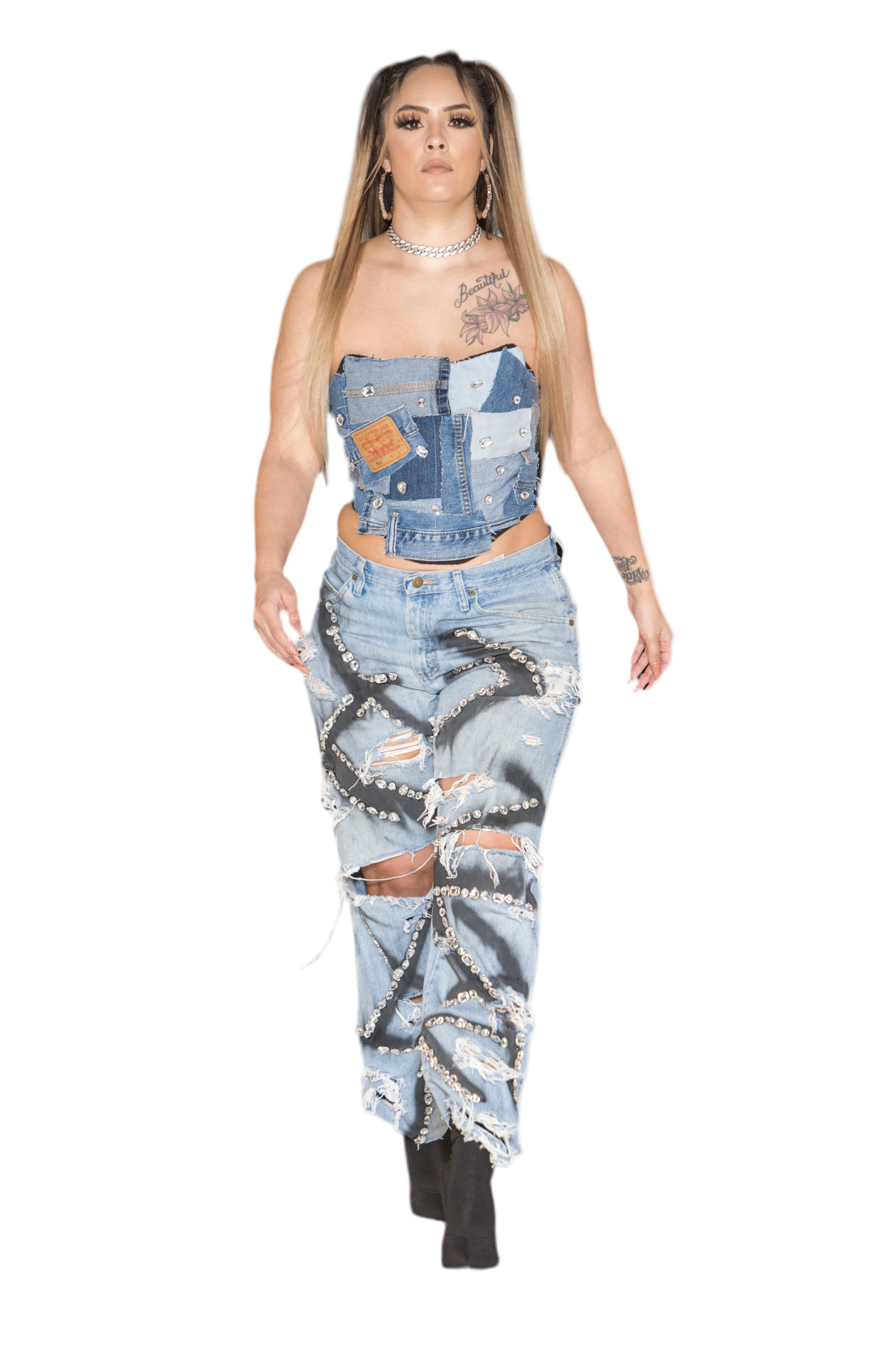 A person wearing a blue denim corset with embellishments and a top over it, standing against a white background.