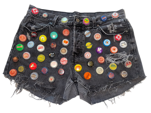 Black denim shorts with colorful bottle caps attached 