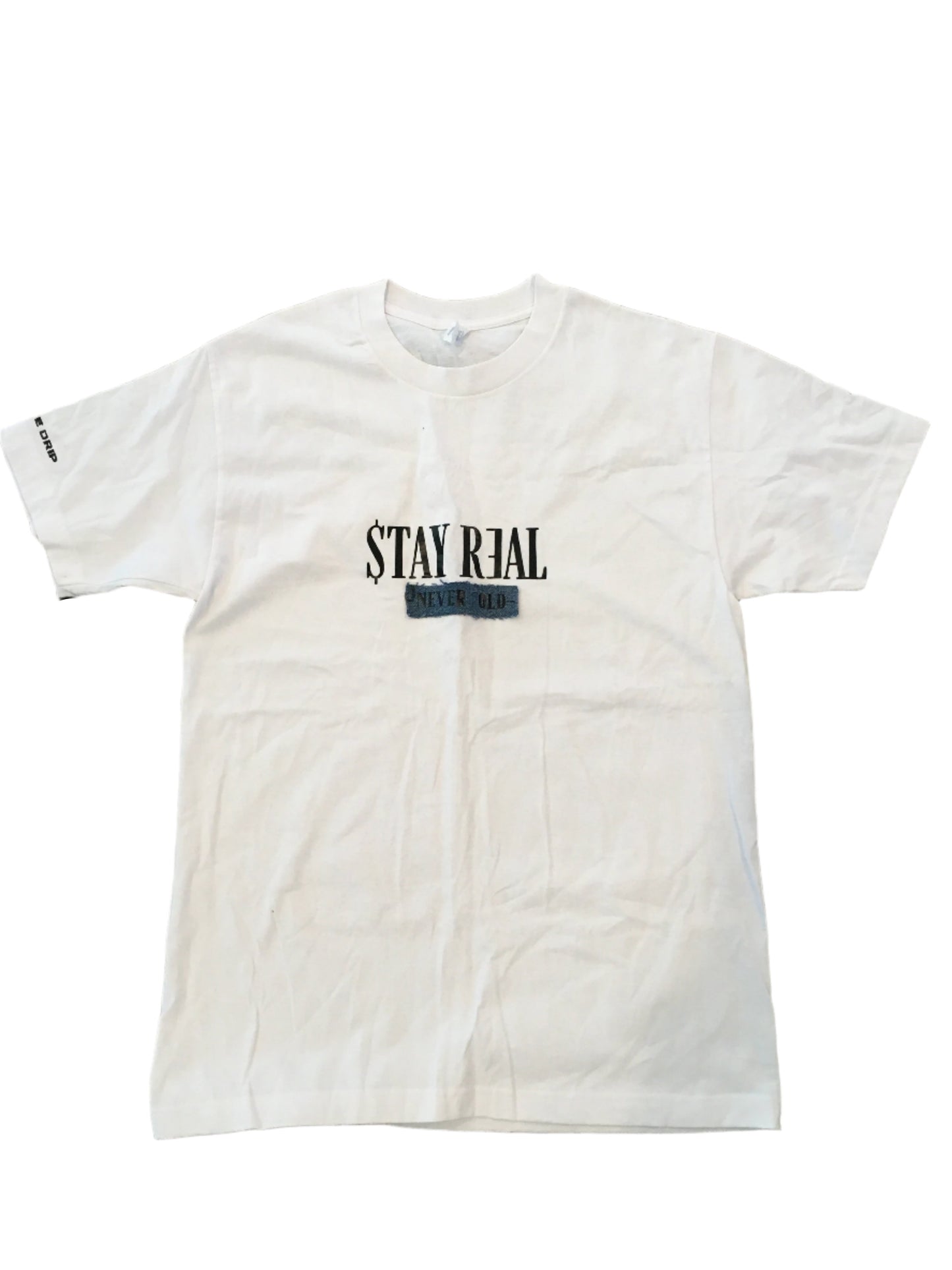 White cotton T-shirt featuring a denim patch with "Stay Real" in the center. "Creative Drip" is printed on the right sleeve for a subtle branded touch. Comfortable and versatile for everyday wear.