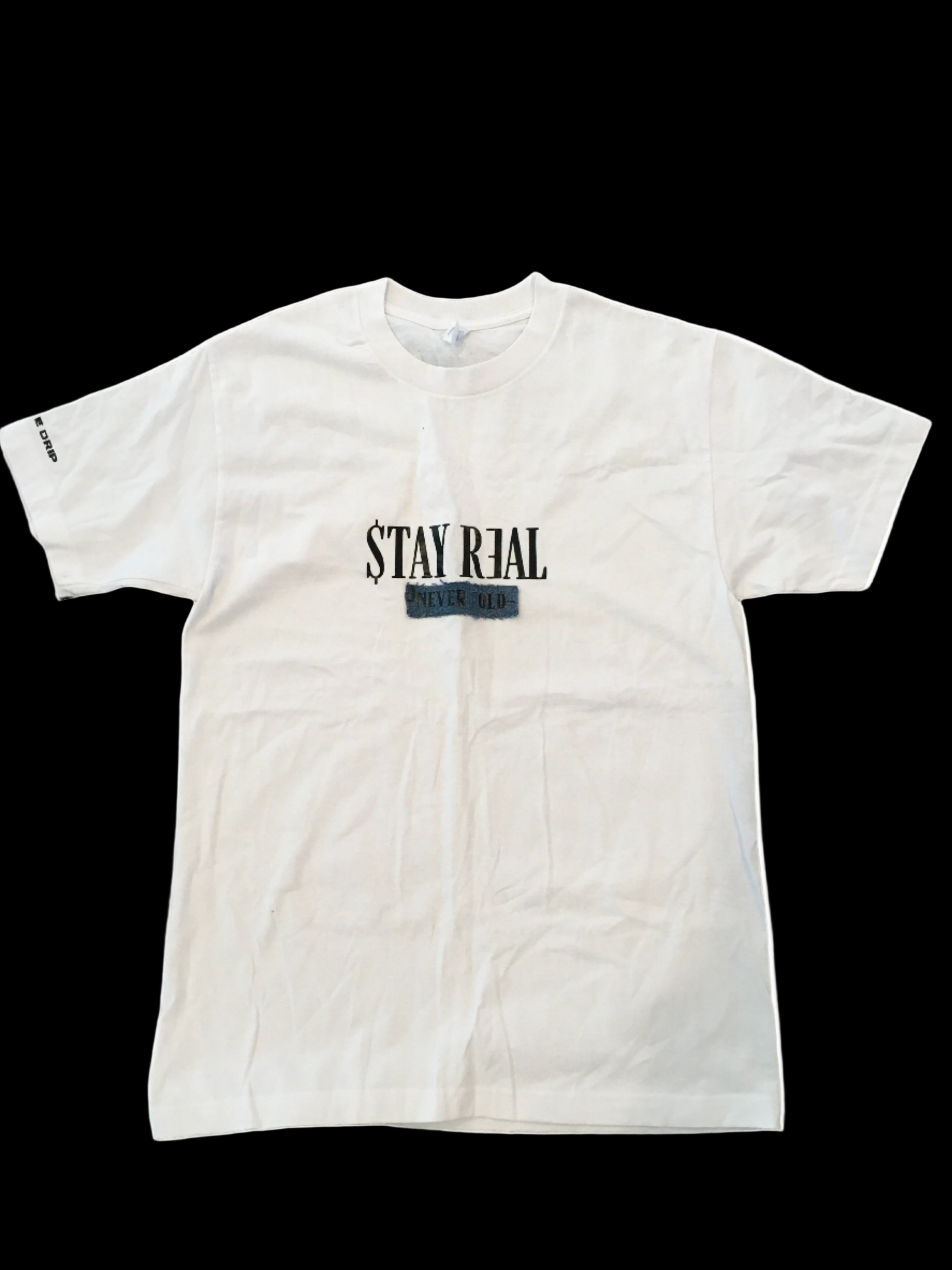 White cotton T-shirt featuring a denim patch with "Stay Real" in the center. "Creative Drip" is printed on the right sleeve for a subtle branded touch. Comfortable and versatile for everyday wear.