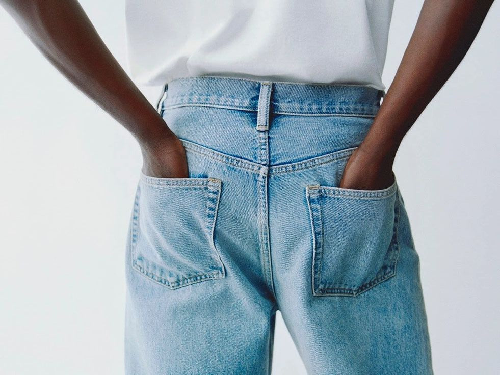 Person wearing blue jeans with a white shirt on a light gray background