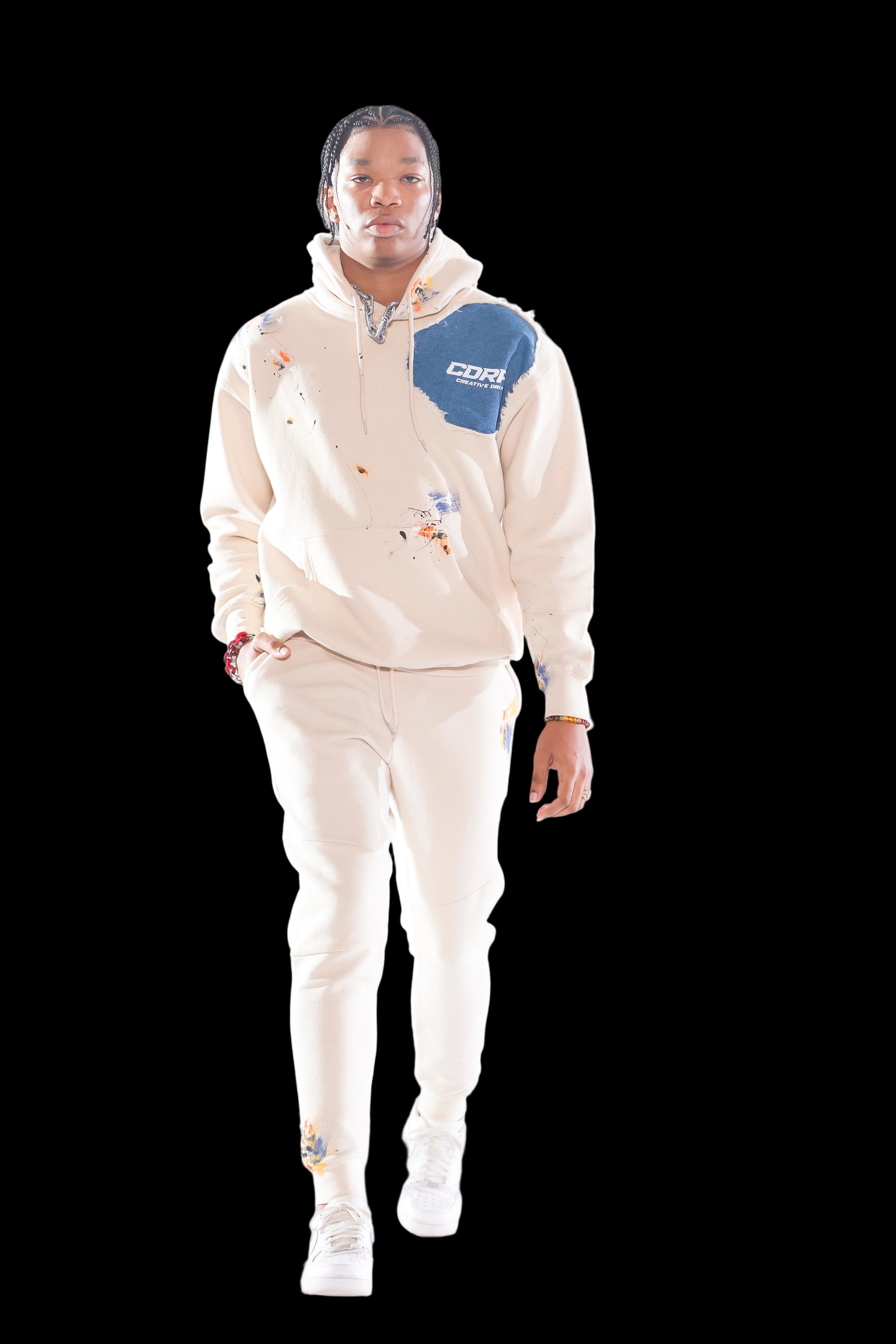 A model wearing high-waisted beige joggers with a hoodie featuring a colorful graphic design, and white sneakers.