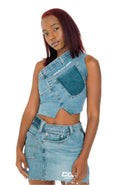 A person wearing a blue denim asymmetrical top and mini skirt with a zipper and button closure.